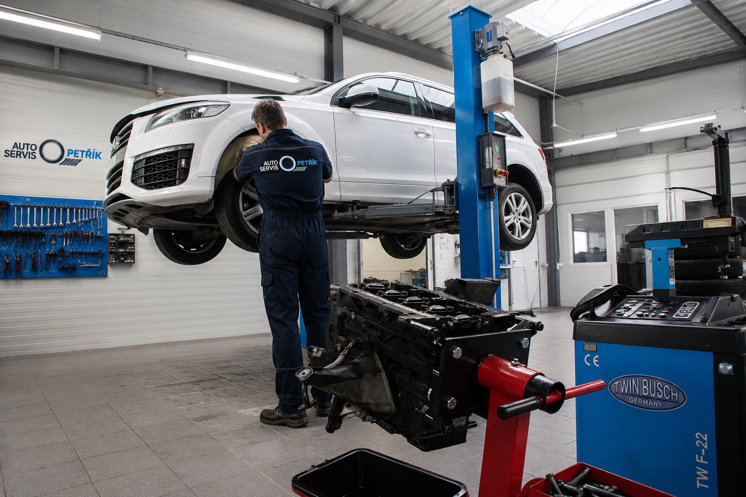 Mechanik u vozu na zvedáku s motorem v popředí